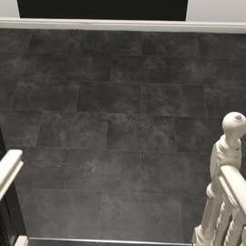 Dark wood‑effect luxury vinyl tile on staircase treads, featuring slip‑resistant nosing and a robust finish for safe, stylish stairways.